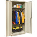A tan Hallowell metal wardrobe cabinet with solid doors filled with clothes and tools.
