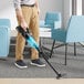 A man using a Makita cordless stick vacuum to clean a room.