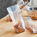 A person using a Choice plastic bag to put pretzels in.