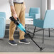 A person using a Makita cordless stick vacuum to clean a floor.