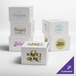 A group of white Baker's Lane cake boxes with purple, brown, and black text logos.