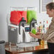 A woman pouring a drink into a Bunn slushy machine.