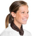 A woman wearing a white chef's coat and brown chef neckerchief over a white shirt.