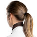 A woman wearing a brown chef neckerchief with a ponytail.
