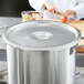 A Vollrath stainless steel cover on a large metal pot.