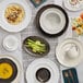 A table set with Acopa Warm Gray scalloped rim platters, white plates, and food.