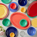A group of colorful plates and bowls on a table with a blue plate and a green bowl.