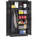 A black metal Tennsco combination cabinet with solid doors and items on it.