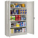 A light gray Tennsco jumbo storage cabinet with solid doors filled with many items.