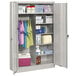 A light gray Tennsco metal combination cabinet with solid doors and items on the shelves.