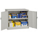 A light gray Tennsco jumbo storage cabinet with solid doors filled with boxes and files.
