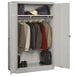 A light gray metal Tennsco jumbo wardrobe cabinet with solid doors holding clothes and shoes.