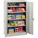 A Tennsco light gray metal storage cabinet with shelves full of items.
