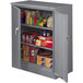 A dark gray Tennsco deluxe metal storage cabinet with shelves full of boxes and other items.