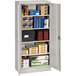 A light gray Tennsco metal storage cabinet with solid doors and shelves holding many boxes.