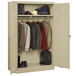 A sand metal Tennsco wardrobe cabinet with clothes and luggage.