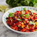 A bowl of black bean and corn salad with limes and parsley.