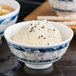 A close up of a Thunder Group Blue Dragon melamine rice bowl filled with rice and black sesame seeds.