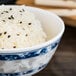 A Thunder Group Blue Dragon melamine rice bowl filled with rice and black sesame seeds.