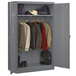 A gray metal Tennsco jumbo wardrobe cabinet with clothes and bags.