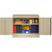 A sand Tennsco storage cabinet with books and folders inside.