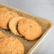 A MFG Tray Goldtex fiberglass bakery display tray holding cookies on a wooden surface.