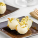 Three white chocolate balls with pistachio and nuts on a plate with Callebaut Ice White Chocolate.