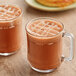 Two glass mugs of hot chocolate made with Callebaut Ground Dark Chocolate.