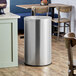A Lancaster Table & Seating stainless steel trash can with decorative accents.