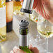 A hand using a Vacu Vin wine stopper to seal a bottle of white wine.