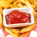 A CAC Super White scalloped edge porcelain sauce dish filled with ketchup on french fries.