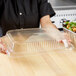 A hand placing a clear plastic lid on a Durable Packaging steam table pan.