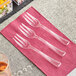 A group of Visions clear plastic tasting forks on a pink napkin.
