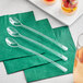 A group of clear plastic Visions tasting spoons on green napkins.