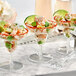 A group of Visions clear plastic mini margarita glasses filled with shrimp and avocado.