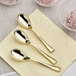 A close-up of Visions gold plastic tasting spoons on a napkin next to bowls of ice cream.