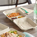 World Centric 3-compartment compostable container filled with food on a table.