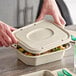 A person holding a World Centric compostable fiber lid on a container of food.