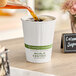 A cup of coffee being poured into a white World Centric compostable paper hot cup.