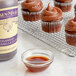 A chocolate cupcake with brown frosting and Nielsen-Massey Ugandan Vanilla Extract on a cooling rack.