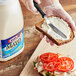 A person spreading Kraft Light Mayonnaise on a sandwich in a professional kitchen.