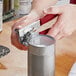 A person using a Swing-A-Way handheld can opener to open a can.