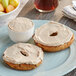A bagel with Cinnamon Bun Cream Cheese spread on a plate with fruit.