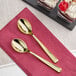 Two Visions gold plastic tasting spoons on a pink napkin.