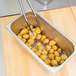 A Vollrath stainless steel wire pan grate in a metal container with food in it.