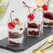 Three Choice clear plastic mini angled appetizer cups filled with chocolate and cherry desserts.