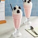 Two glasses of pink milkshakes made with Oringer Black Raspberry Milkshake Base and topped with blackberries and whipped cream.