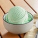 A bowl of green peppermint ice cream with a scoop of Oringer Peppermint Hard Serve Ice Cream Flavoring.