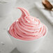 A bowl of pink Oringer Strawberry Dream soft serve ice cream with a spoon.