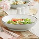 An Acopa Embers stoneware pasta bowl filled with salad on a table with a fork.